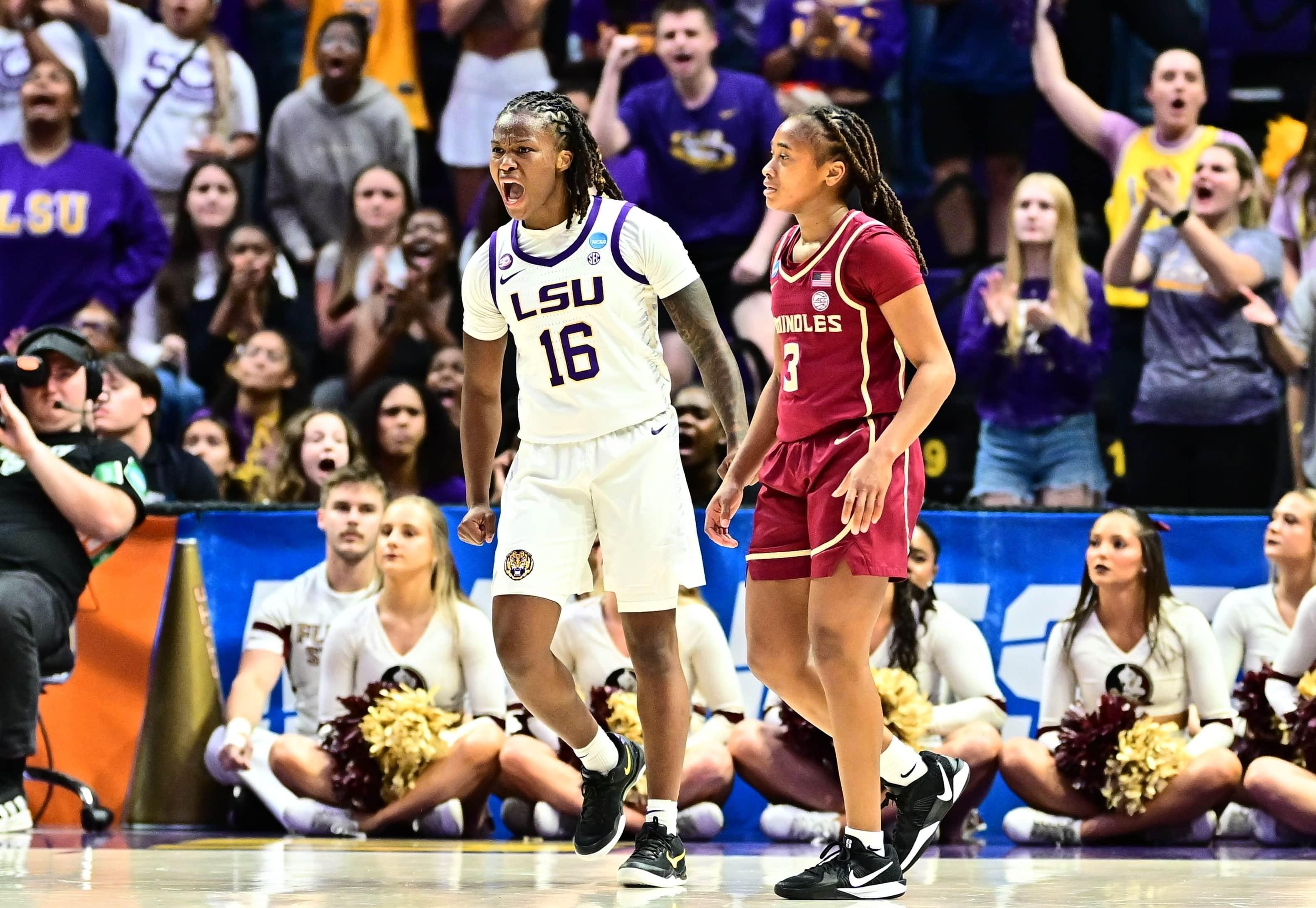 A women's basketball player celebrates in front of a screaming crowd.