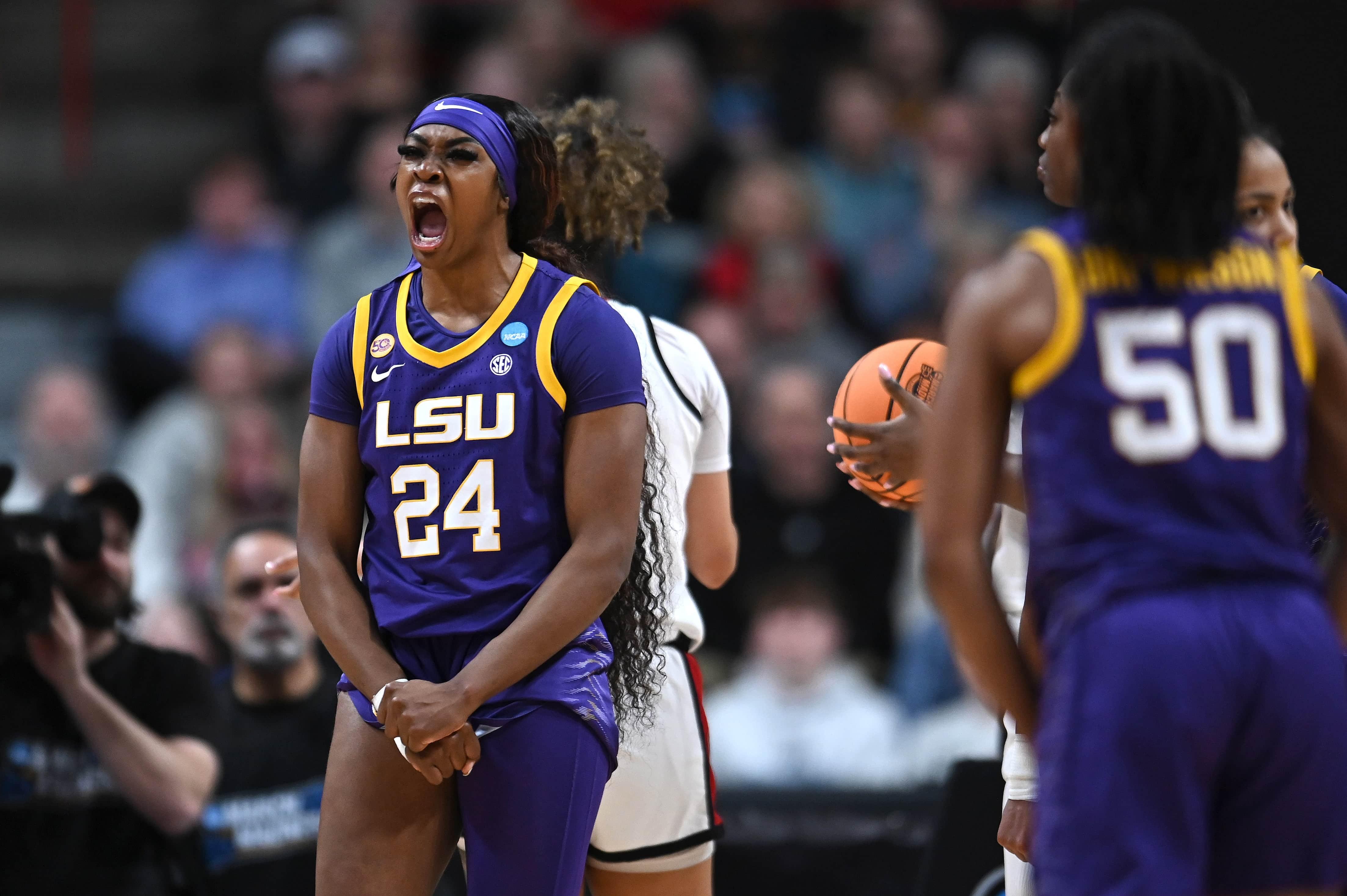 A women's basketball player celebrates in front of her teammates.